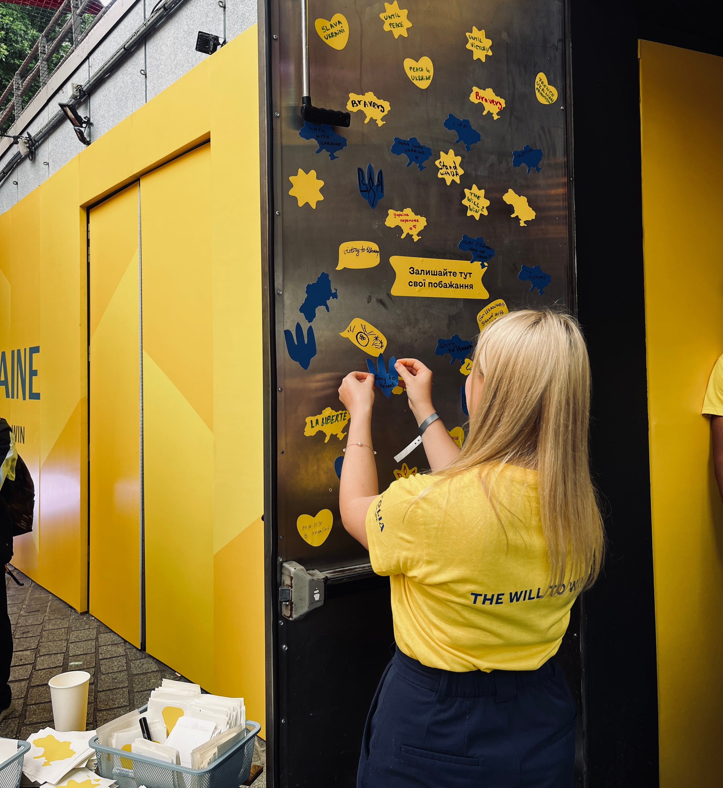 Des bénévoles et supporters inscrivent des messages d'espoir sur la porte de la Maison olympique ukrainienne, le 27 juillet 2024.