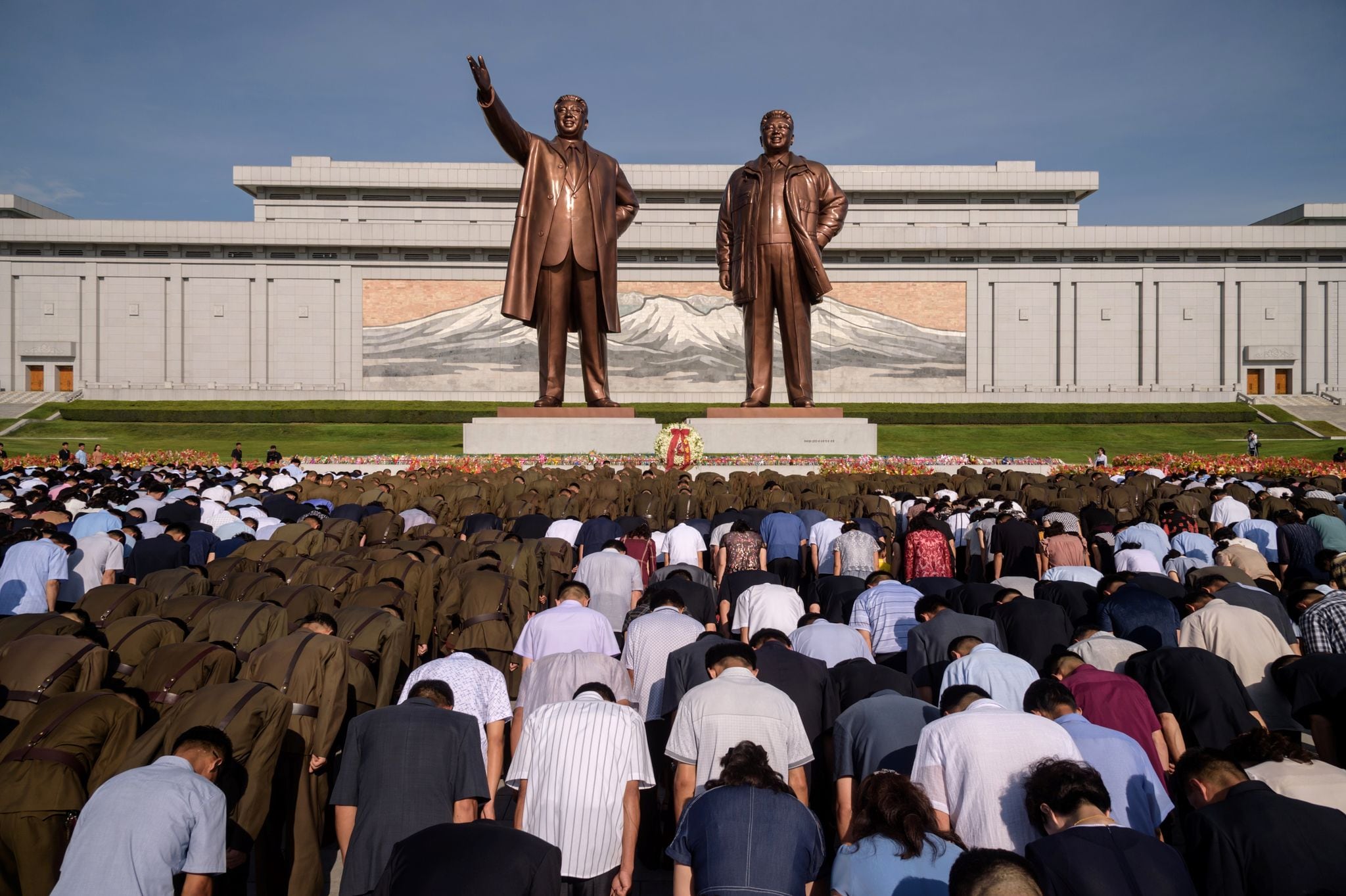 La foule s'incline devant les statues des dirigeants nord-coréens défunts Kim Il Sung et Kim Jong Il à l'occasion du 25e anniversaire de la mort de Kim Il Sung, à Pyongyang le 8 juillet 2019