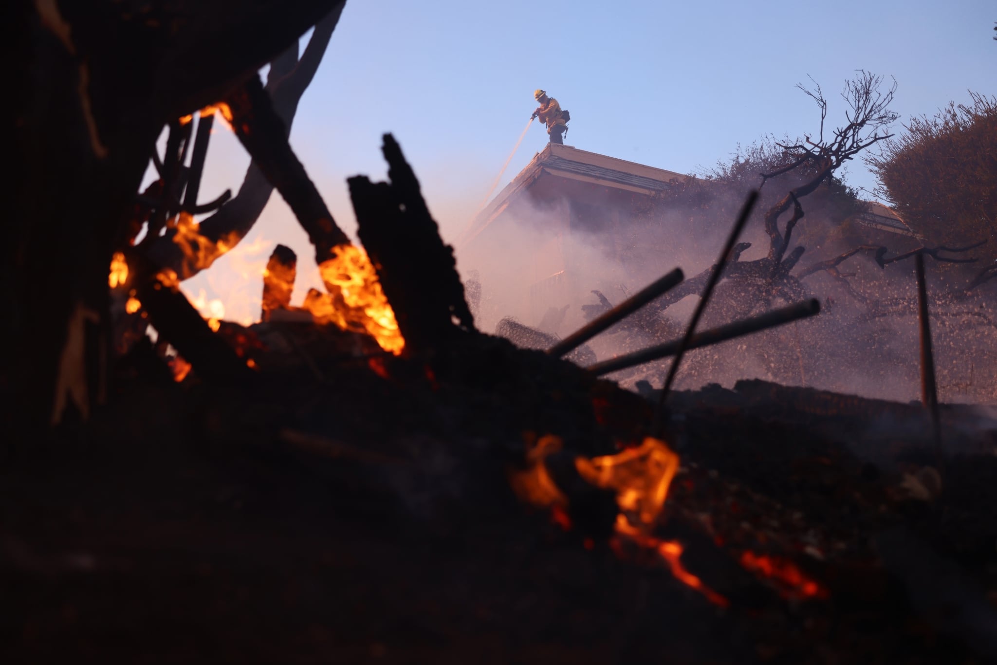 Un pompier lutte contre les braises d'un incendie dans le quartier de Pacific Palisades, aux portes de Los Angeles, le 7 janvier 2025